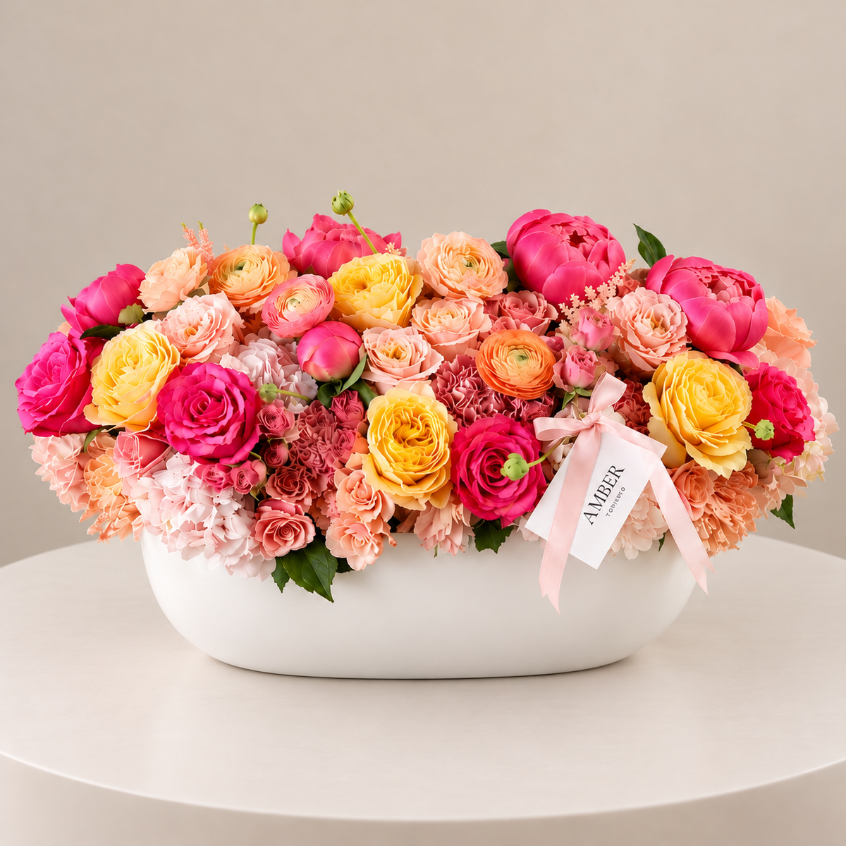 Sunset Muse large statement flower arrangement with pink, peach, coral and yellow flowers in a white oval vase by Amber Flowers Toronto